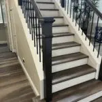 Wooden staircase with black metal railing.