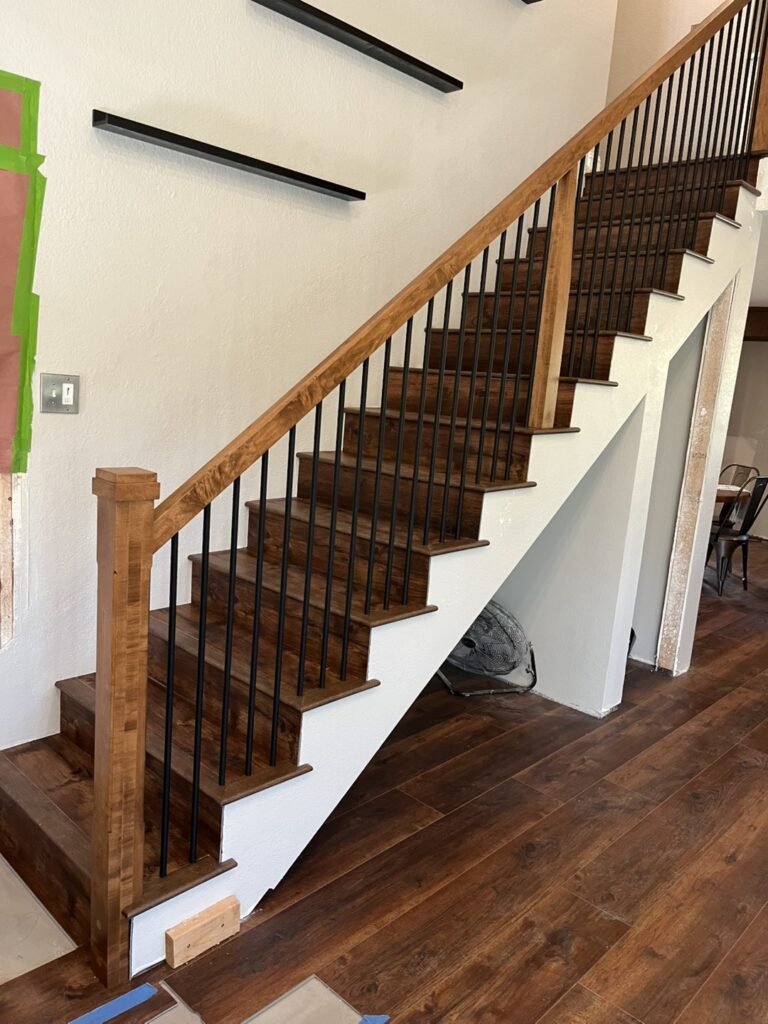 Wooden staircase with metal railings and shelves.