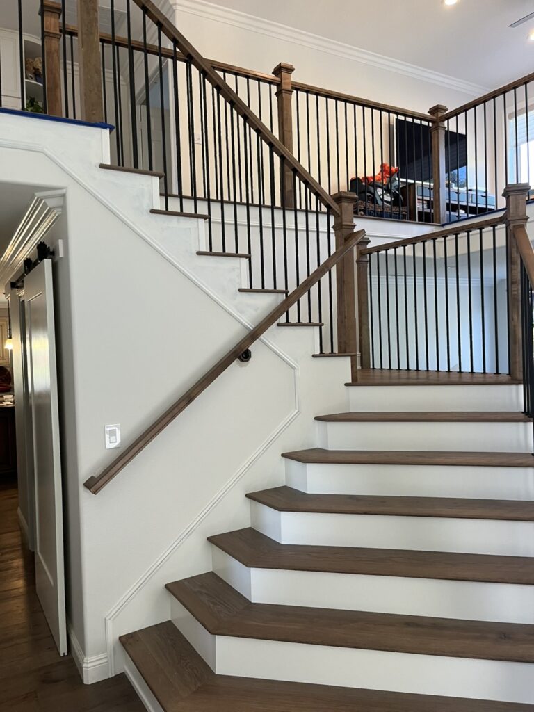 Wooden staircase with black metal railings.
