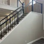 Modern staircase with black metal railing.